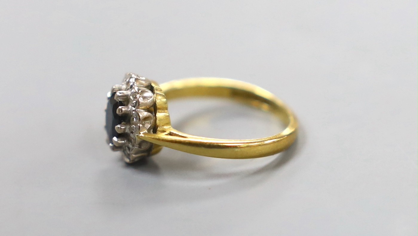 A modern 18ct gold, sapphire and diamond chip set oval cluster ring, size G, gross weight 3.1 grams.